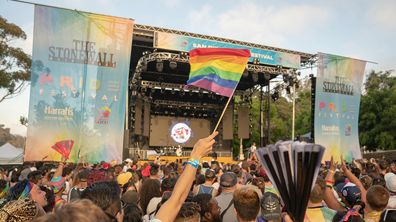 View of the Stonewall Stage with a large crowd and arm holding a Pride flag