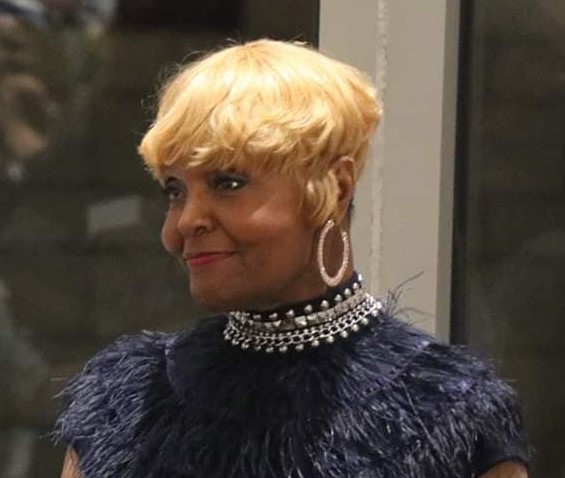 Tracie Jada Obrien, a black trans woman, with blond hair and a black feather dress