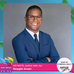 Reggie Greer headshot. Reggie is wearing a navy blue suit, his arms are crossed and he's wearing glasses. He's smiling. 