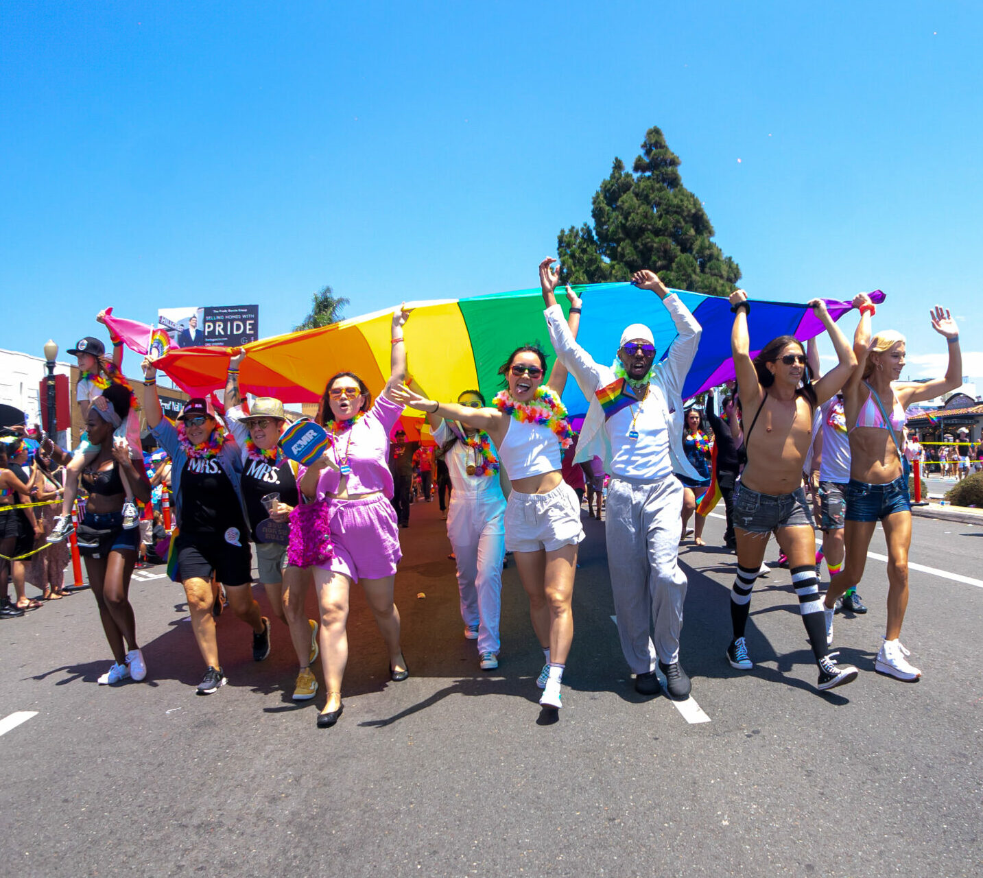 Parade attendees holding giant rainbow flag