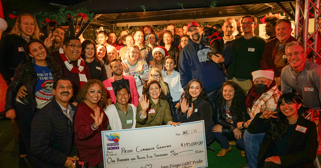 San Diego Pride posing and smiling behind a big check honoring the community grants