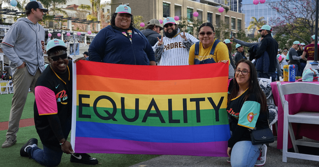 OATP attendees smiling and holding a rainbow flag with the word "EQUALITY" on it
