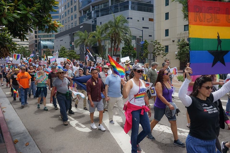 Protesters hold signs and flags marching int he Equality March 